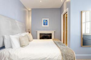 Un dormitorio con una cama blanca y una chimenea en Brightonwave, en Brighton & Hove