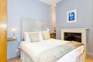 1 dormitorio con 1 cama blanca grande y chimenea en Brightonwave, en Brighton & Hove
