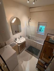 Appartement La Vanne Confortable et équipé في لابريس: حمام مع حوض وحوض استحمام ومرآة +27 صورة