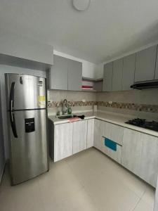 Casa Moderna en Condominio Ricaurte - Girardot في جيراردو: مطبخ مع ثلاجة ستيل ستانلس ودواليب بيضاء