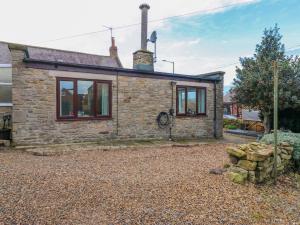 a stone cottage on a gravel driveway at Mains Cottage in Consett