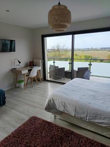 Villa'vi Lyon Est Chambres d'Hôtes في سانت-بريست: غرفة نوم بها سرير ومكتب ونافذة كبيرة