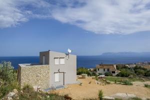 a white house on a hill with the ocean in the background at Villa Rosaria vicino la Riserva dello Zingaro in Scopello