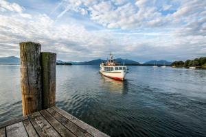 a white boat on the water near a dock at Berghotel Lindenhof in Siegsdorf