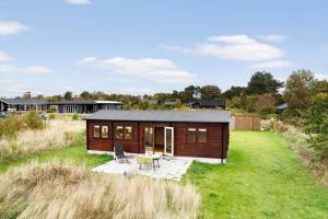 a wooden cabin in a field with a table and chairs at 20158-Samso-Laerkevej-13 in Mårup