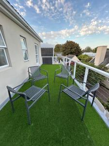 three chairs sitting on a balcony with green grass at Serenity Green House near Constantia Winelands in Square Hill +4 photos