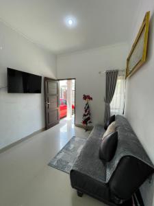 ein Wohnzimmer mit einem schwarzen Sofa und einem TV in der Unterkunft Cozy Homes BnB in Prampuan