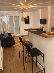 a living room with a bar with chairs and a couch at Beau 2 pièces moderne et cosy à Corbeil-Essonnes in Corbeil-Essonnes