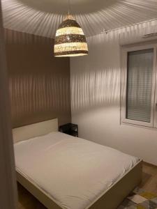 a bedroom with a white bed and a chandelier at Beau 2 pièces moderne et cosy à Corbeil-Essonnes in Corbeil-Essonnes