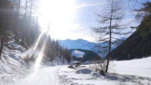 a snow covered road with the sun shining on a mountain at Apart Stefan Niederthai in Niederthai