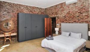 a bedroom with a large bed and a brick wall at Winelands Manor Vineyard Views in Riebeek-Kasteel