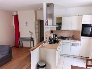 a small kitchen with white cabinets and a couch at Prieuré Maisons-Laffitte in Maisons-Laffitte