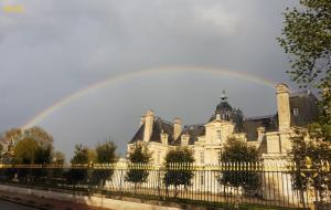 a rainbow over a building with a fence at Prieuré Maisons-Laffitte in Maisons-Laffitte