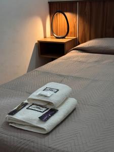 Una cama con dos toallas y un espejo. en Hotel Santa Bárbara, en La Falda