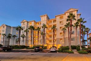 Coastal Breeze Luxurious Coastal Villa Steps to Cinnamon Beach Beautiful Pools! Perfect for Families في Hawthorne: مبنى كبير به أشجار نخيل في موقف السيارات