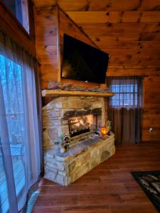a living room with a stone fireplace with a flat screen tv at The Bearfoot Cabin! Ideally located, decorated for Christmas, Fireplace, Game Room! in Sevierville