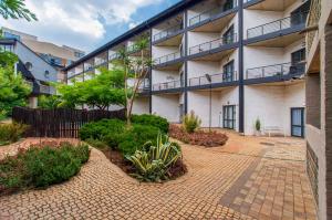 ein Mehrfamilienhaus mit einem gemauerten Gehweg in einem Innenhof in der Unterkunft Blue Haven on Craftmanship Hotel with WiFi Pool & Parking in Johannesburg
