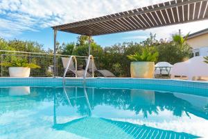 a swimming pool with a pergola next to a house at Casa Boletes, with splendid views! in Cartagena