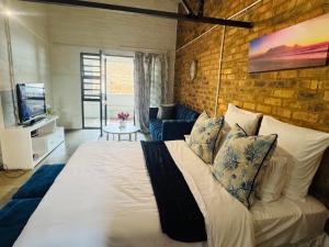 ein Schlafzimmer mit einem großen Bett und einer Ziegelwand in der Unterkunft Blue Haven on Craftmanship Hotel with WiFi Pool & Parking in Johannesburg