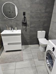 a bathroom with a toilet and a sink and a washing machine at Сучасна квартира в новобудові біля луцького кільця in Rivne +10 photos