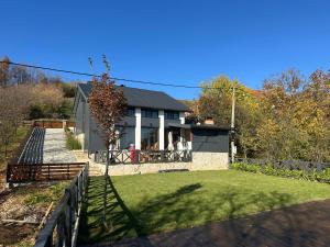 a house with a fence and a yard at Vikendica Dedovina selo Negrišori-Lučani in Lučani