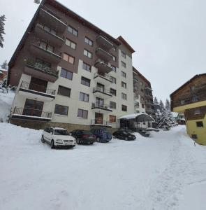 un aparcamiento cubierto de nieve frente a un edificio en Apartman Miki, en Vlašić