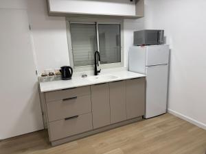 una cocina con fregadero y refrigerador en Bimat HaTzafon, en Kiryat Shemona