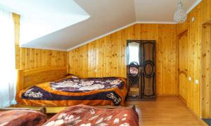 Guest House Nukri في Danisparauli: سريرين في غرفة ذات جدران خشبية +صورتان