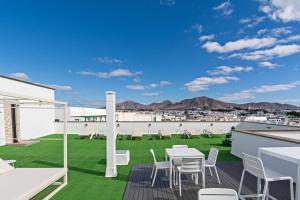 Un patio en la azotea con sillas blancas y césped verde. en Apartment Limonade Deluxe Main Center Playa Blanca By PVL, en Playa Blanca