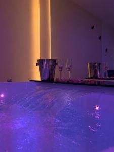 a group of wine glasses on a table with purple lights at Elite Suite in Castellana Grotte