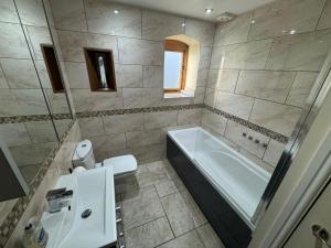 a bathroom with a tub and a toilet and a sink at Woodland Forge - The Stables in Over Whitacre +21 photos