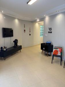 een woonkamer met een flatscreen-tv aan de muur bij Apto Vista Mar com Ar cond, Piscina, Wifi, TV e Garagem 2 vagas in São Vicente