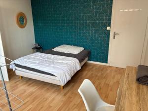 Un dormitorio con una cama y una pared verde. en Green room - Wifi - Centre ville - Cosy, en Annemasse
