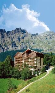 ein Gebäude auf einem Hügel mit Bergen im Hintergrund in der Unterkunft Hotel Alfa Superieur - Leukerbad-Therme in Leukerbad