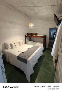 a bedroom with two beds and a chandelier at Pousada Quintal da Praça in Prado