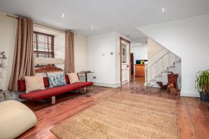 a living room with a red couch and a staircase at The Old Bakehouse - Group Getaway in Llandysul