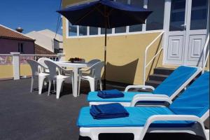 a patio with a table and chairs and an umbrella at Gloria's House in Lagoa