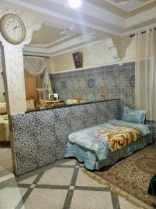 Appartement في Benguerir: غرفة نوم بها سرير وساعة على الحائط