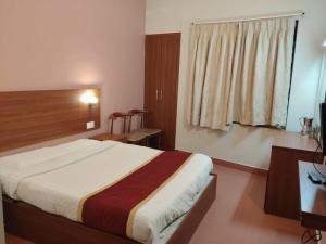 a bedroom with a bed and a desk and a window at Edassery Cokkers tower in Kodaikānāl