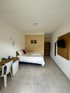 a bedroom with a bed and a desk and a tv at Isadora Pousada in Salinópolis