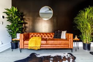 a brown leather couch in a room with plants at Short North Convention King Bed Free Parking! in Columbus