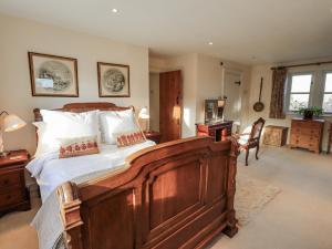 a bedroom with a large wooden bed with white sheets at Orchard House in Leyburn