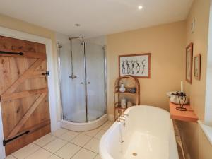 a bathroom with a tub and a shower with a door at Orchard House in Leyburn +30 photos
