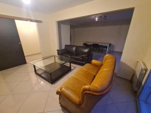 sala de estar con sofá de cuero y mesa de cristal en Large house near Mérignac Airport, en Mérignac