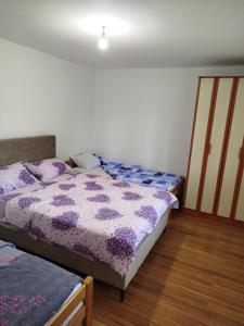 two beds in a bedroom with purple comforter at Apartman M in Trebinje