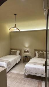 a bedroom with two beds and a table with a lamp at نزل فاخر in Taif