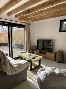 un soggiorno con un divano, una TV e un tavolo di Le refuge de César a Pouzac