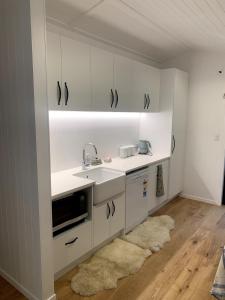a kitchen with white cabinets and a sink and a rug at The woolshed - Oruanui in Oruanui