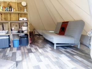 Grande tente au pied du Vercors في Saint-André-en-Royans: أريكة في خيمة مع جهاز كمبيوتر محمول عليها