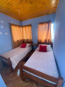 Hermosa casa en Quillón : سريرين في غرفة صغيرة مع وسائد حمراء
